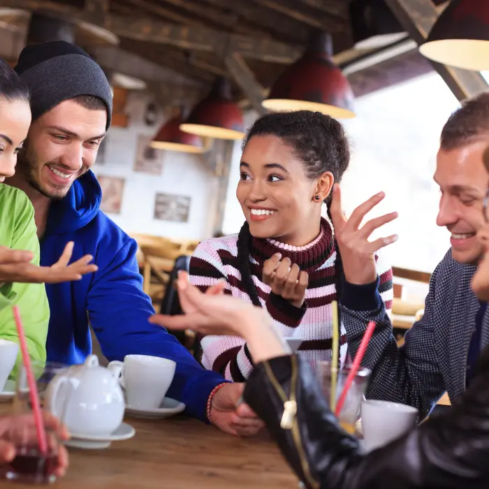 A group of people sitting in a café discussing promotional pins and badges as part of their strategy to raise awareness.