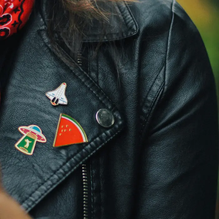 3 custom enamel pins on a ladies leather jacket.