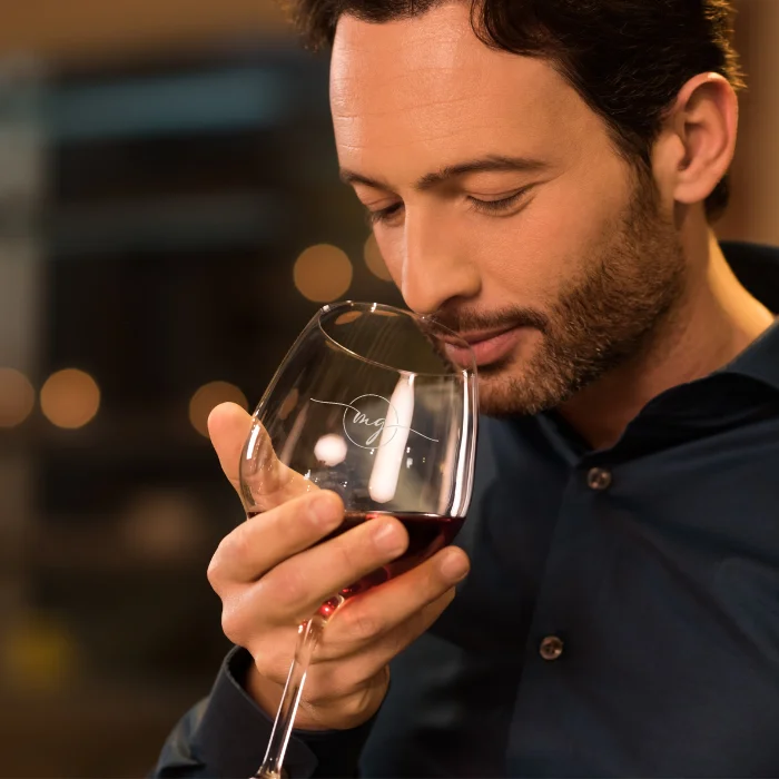 Man enjoys the benefits of a red wine glass to smell the aromas of his wine.