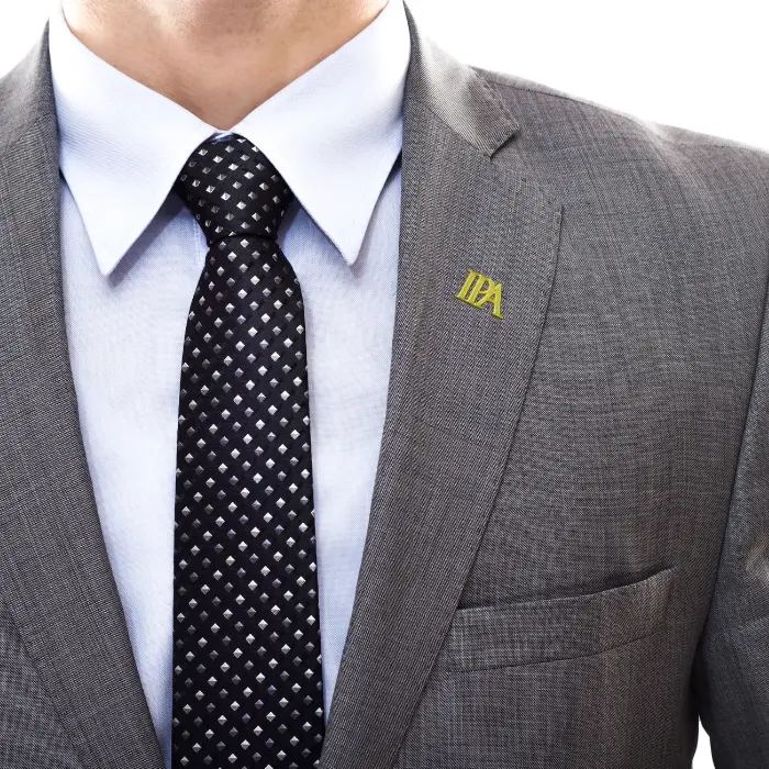 Man wearing a suit and tie with a custom metal lapel pin attached.