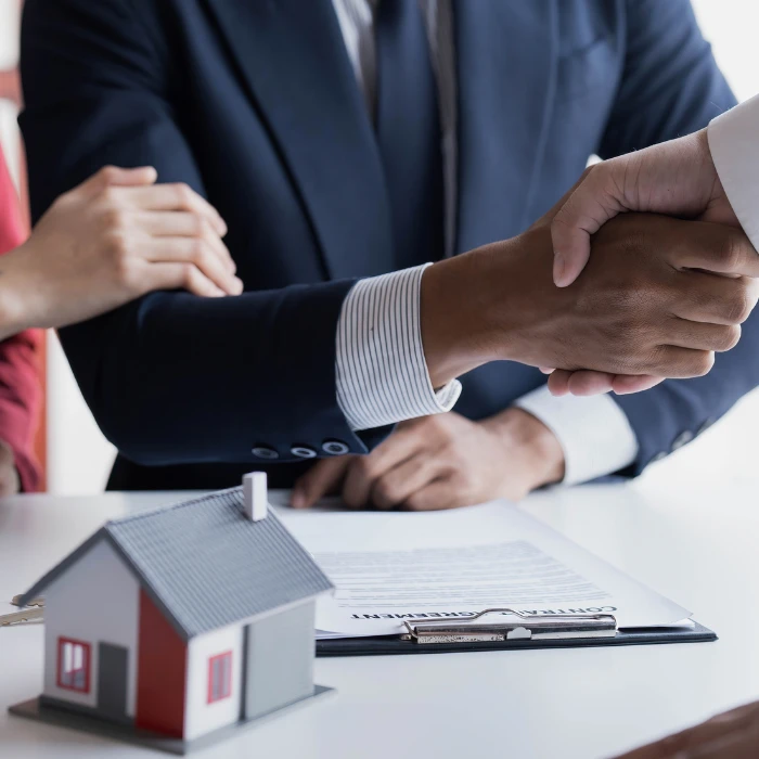 Canadians shake hands at a meeting about purchasing a new home.