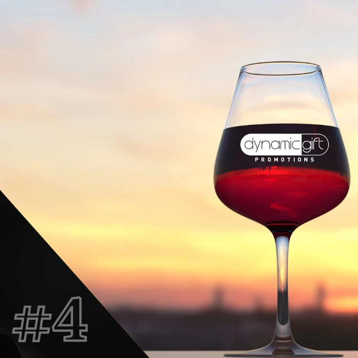 A customized wine glass filled with red wine and branded with Dynamic Gift's logo.